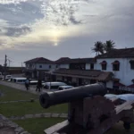 Cannon on the ramparts of Galle Fort at sunset with heritage buildings behind