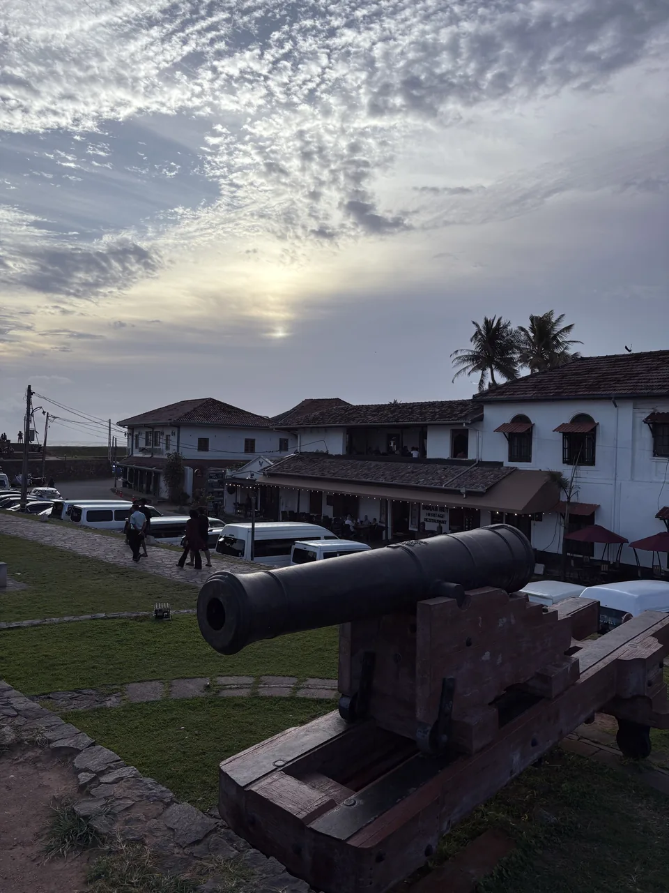 Cannon on the ramparts of Galle Fort at sunset with heritage buildings behind