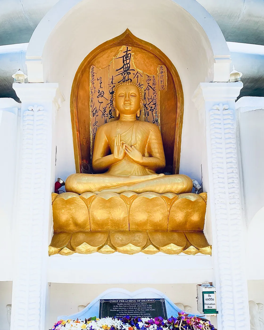 Golden seated Buddha statue in a white niche at the Japanese Peace Pagoda above Jungle Beach