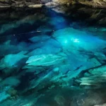 Crystal-clear blue underground pond inside the Nil Diya Pokuna cave near Ella