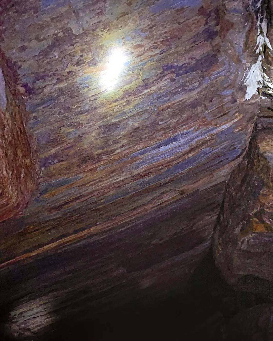 Smooth layered rock ceiling lit by a headlamp inside the Nil Diya Pokuna cave