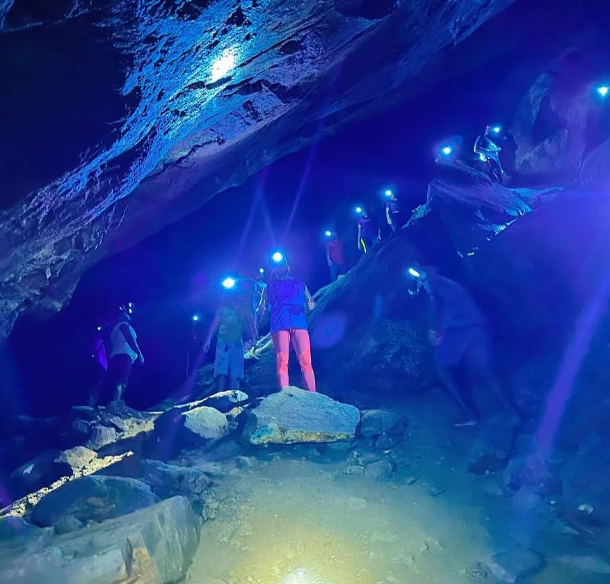 Group of visitors wearing headlamps climbing over rocks inside the Nil Diya Pokuna cave