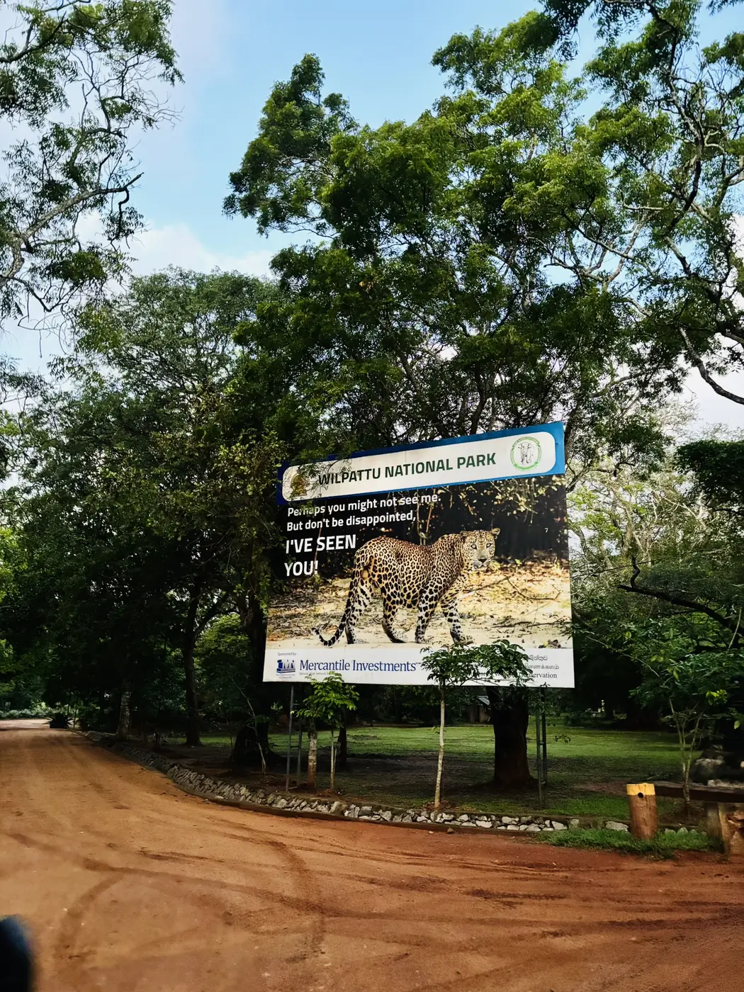 Wilpattu National Park billboard with a leopard beside the dirt road at the main entrance