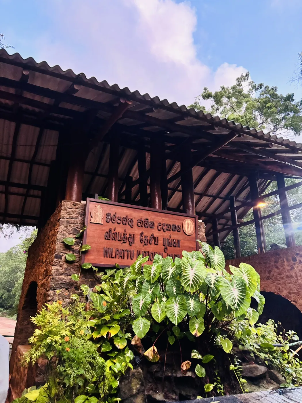 Wooden park gate with the Wilpattu National Park name board and lush green plants